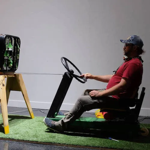 A photo of @cpthardderps riding his interactive lawnmower simulator.