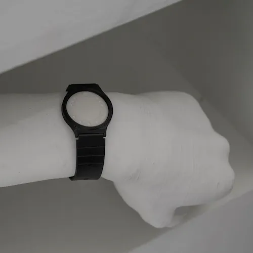 A photo of a white 3D printed arm wearing a modified black casio 'reminder' watch.