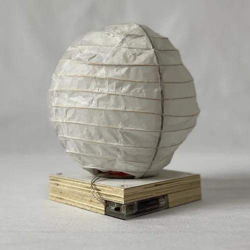 A photo of spherical bamboo desk lamp that is powered by batteries.