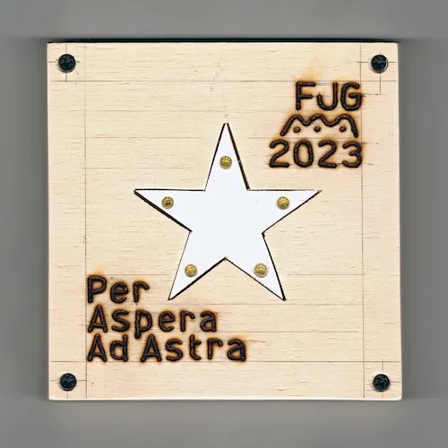 A photo of a white five point star inset into another sheet of plywood.