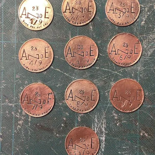 A photo of ten custom copper coins on a green cutting mat.